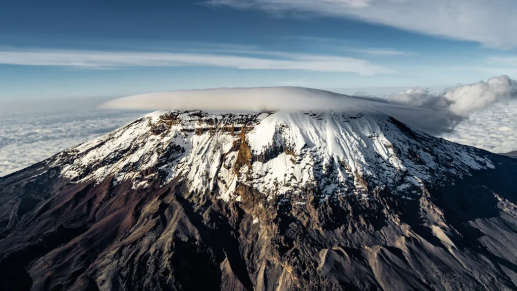 The snow-capped summit of Kibo, Kilimanjaro's highest cone, under a flat lens-shaped cloud