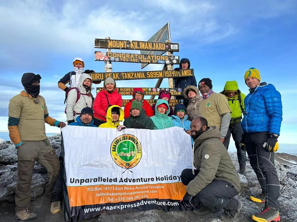 A climbing group with the AAA Express Adventure banner at the summit of Kilimanjaro