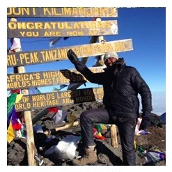 David Metili, mountain guide, at the Uhuru Peak sign