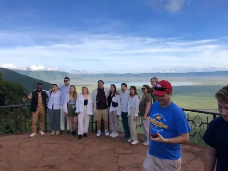 A group of travellers with their guide at the Ngorongoro Crater rim viewpoint, the crater floor far below